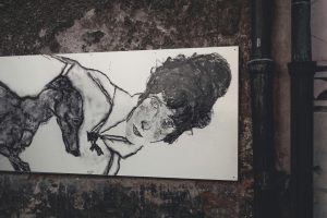 Street art depicting a woman and a dog on a textured wall in Český Krumlov.