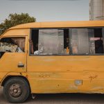 A worn yellow bus navigating a city street, portraying urban transportation and daily life.
